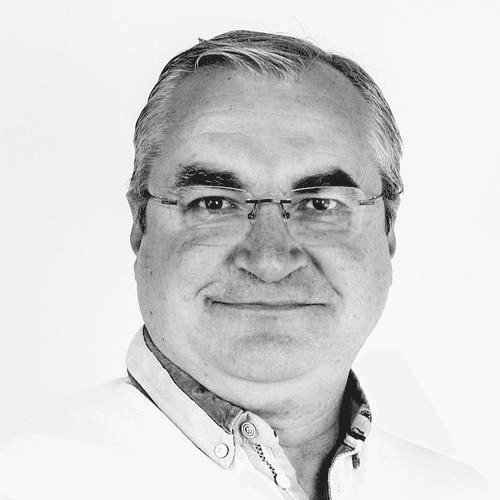 Black and white portrait of an older man with glasses, smiling and wearing a collared shirt.