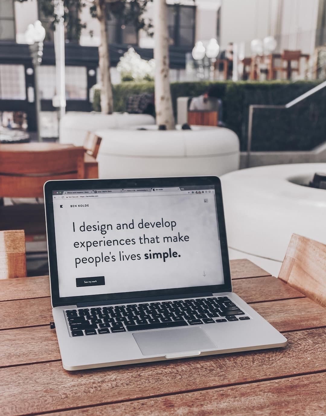 Open laptop on a wooden table with text about design and development that makes lives simple.