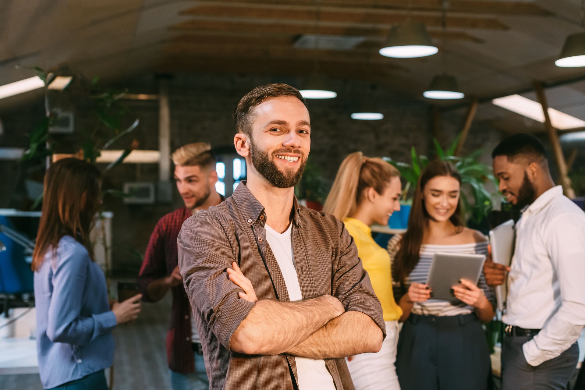Gestionnaire de Smm souriant à l'appareil-photo, restant dans le bureau créateur occupé